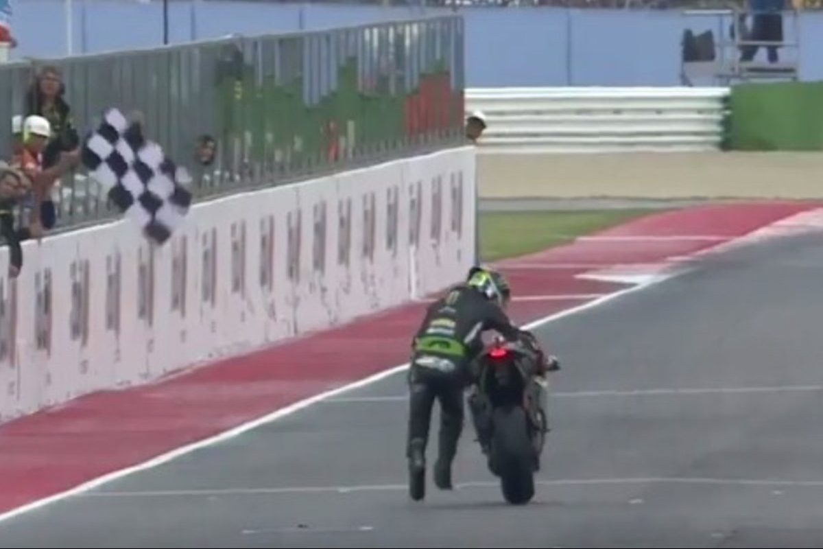 motorcycle racer pushes bike to finish line