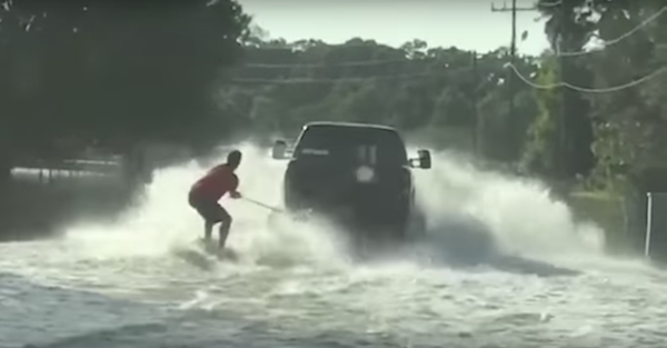 A lifted truck pulls a wake boarder along the flooded streets of Texas