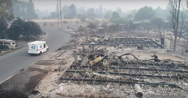 A drone shows footage of a postal worker delivering mail to an area destroyed by wildfires