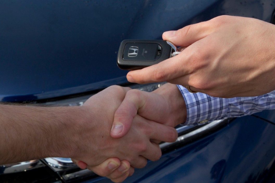 car salesperson handing over keys