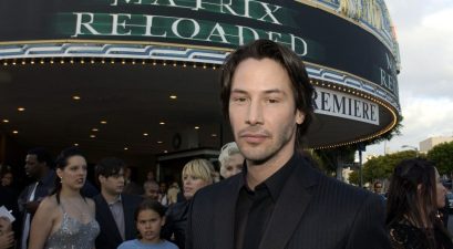 keanu reeves standing outside a matrix reloaded marquee