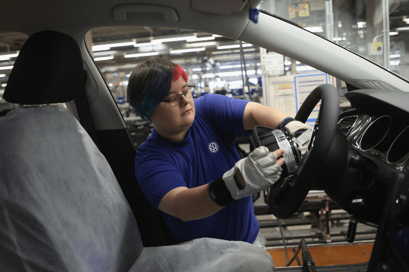 An employee installs an airbag into the steering wheel of a Golf 7 at the Volkswagen factory