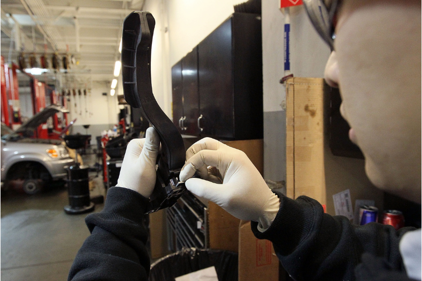 Toyota service technician performs a recall repair on an accelerator pedal from a Toyota Camry