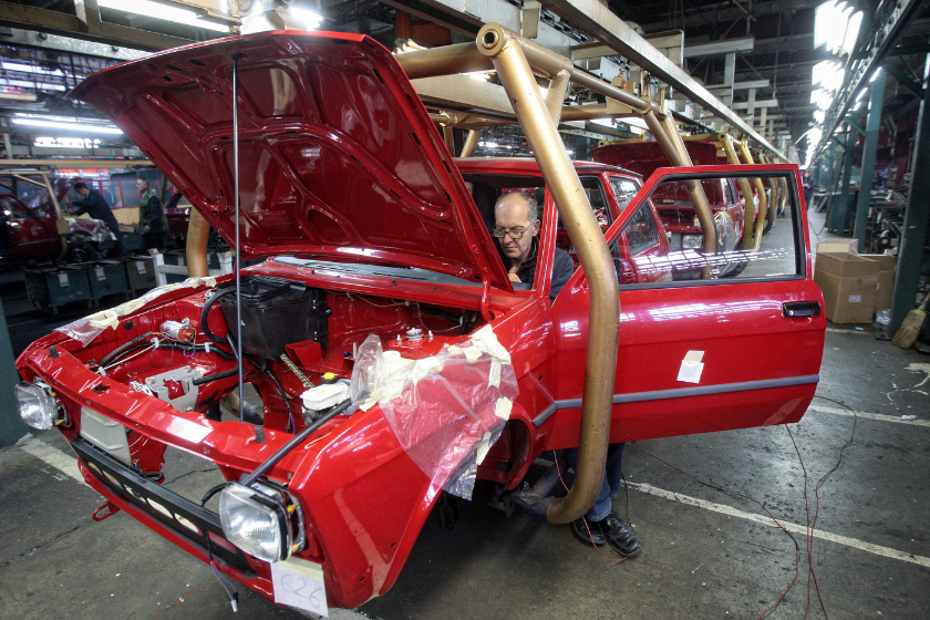 worker inside red yugo on assembly line