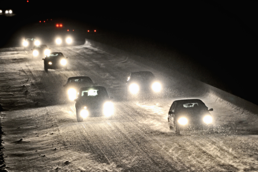 cars driving at night with snow on the ground