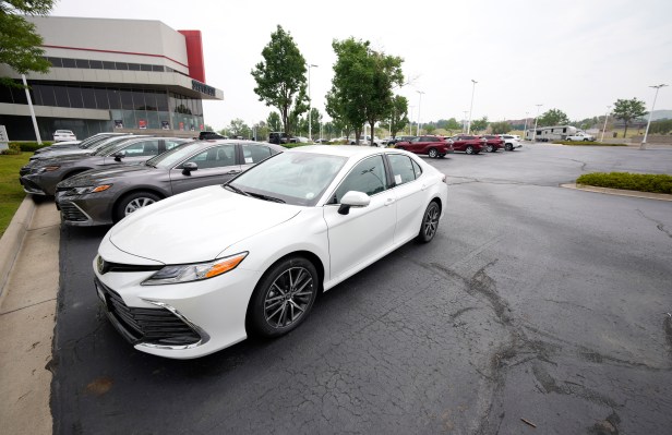 a small collection of unsold 2021 Camry sedans and Highlander sports-utility vehicles sits in an otherwise empty storage lot outside a Toyota dealership