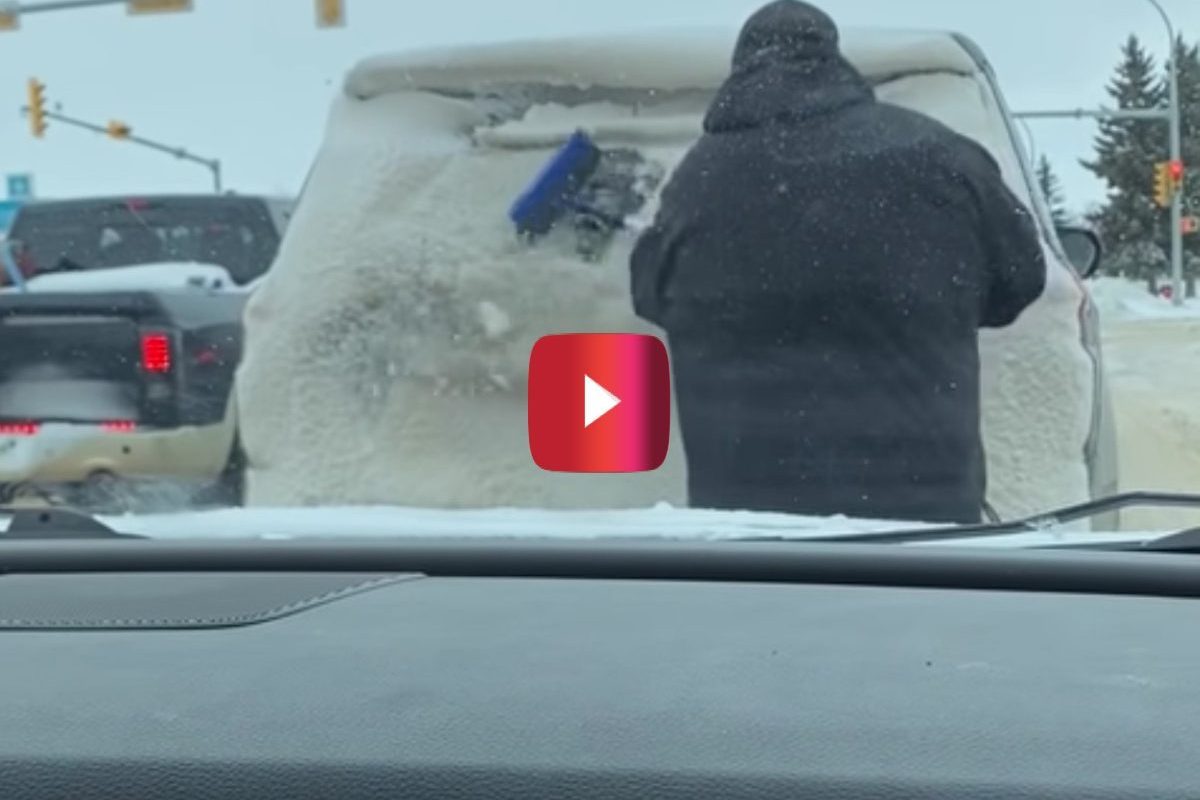 driver brushes snow of car window
